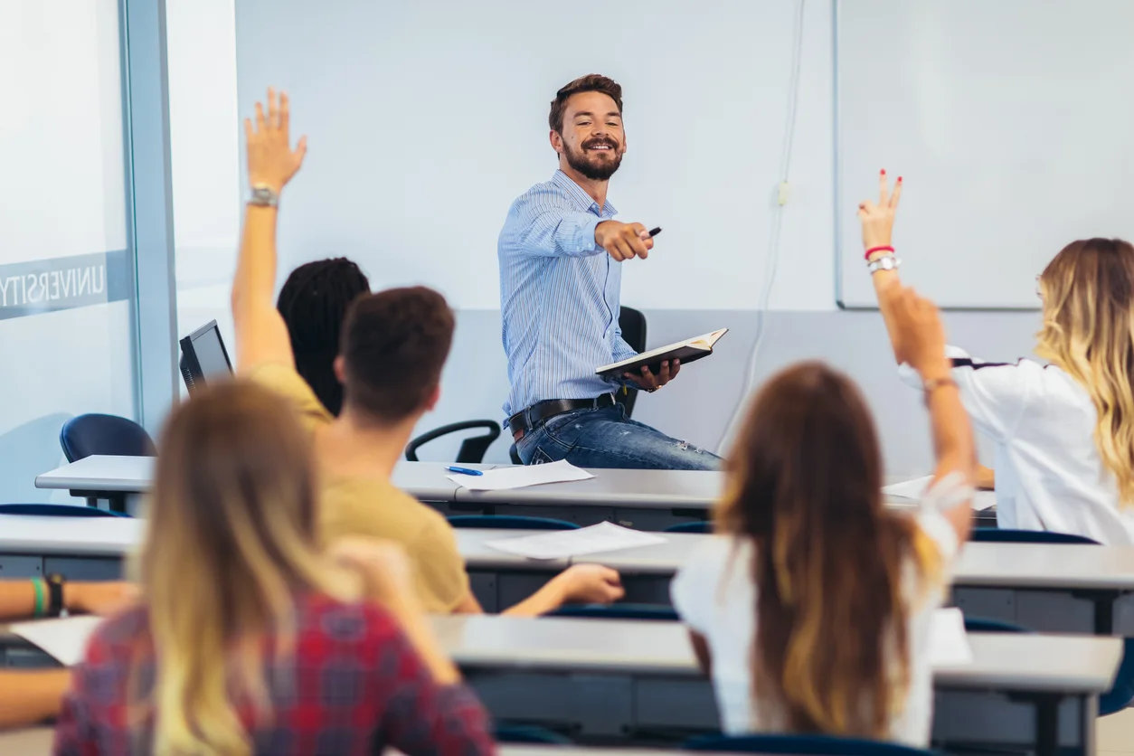 High school students raising hands on a class stock photo