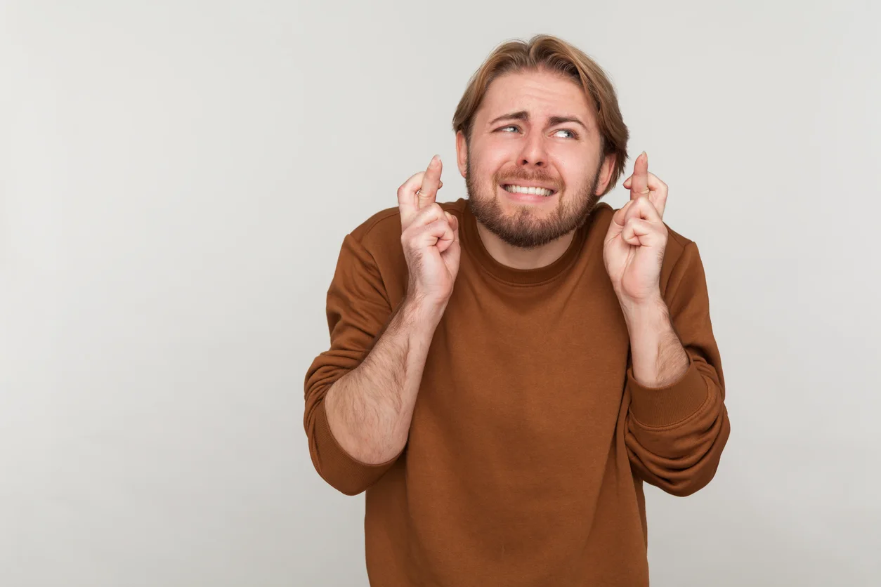 Man with beard crossing fingers for luck, making a wish, dreaming of innermost, ritual. stock photo