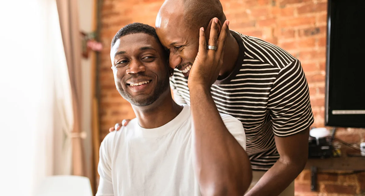 Two black men sharing affection with a gentle touch on the shoulder and face