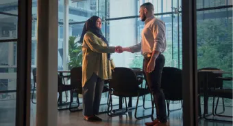 A handshake between an immigrant and a job interviewer in an office.