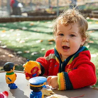 a boy playing with toys outside on a fall day