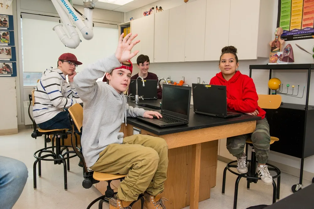 youth in classroom with hand raised