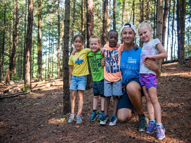 Three campers outdoor, smiling. One camper is holding a soccer ball 