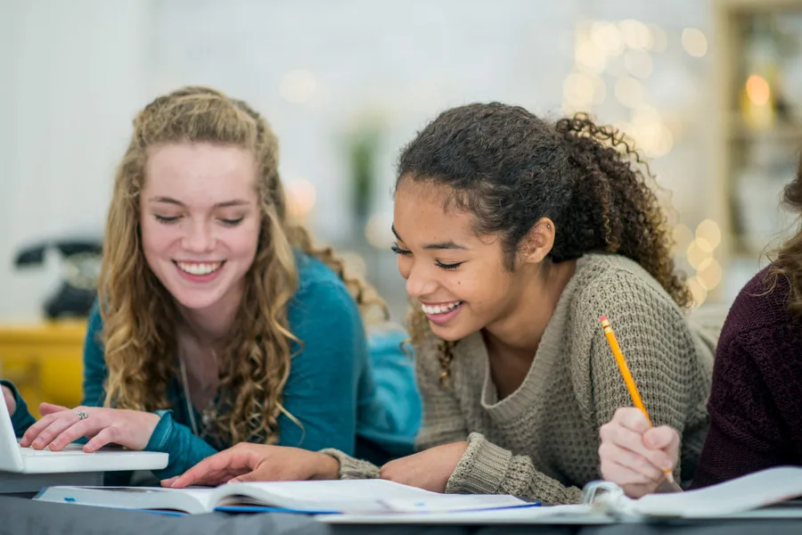 two teenage girls taking notes in a class